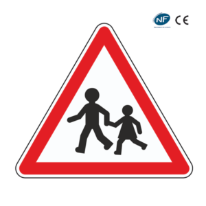 Panneau triangulaire de signalisation avertissant les piétons, avec deux enfants dans le cadre rouge.