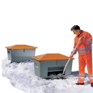 Épandeur trainé en acier de 260 L avec couvercle orange, utilisé dans la neige par un opérateur en tenue haute visibilité orange.