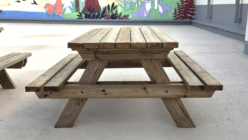 table pique nique en bois dans la cours d'une école posée sur un sol en béton